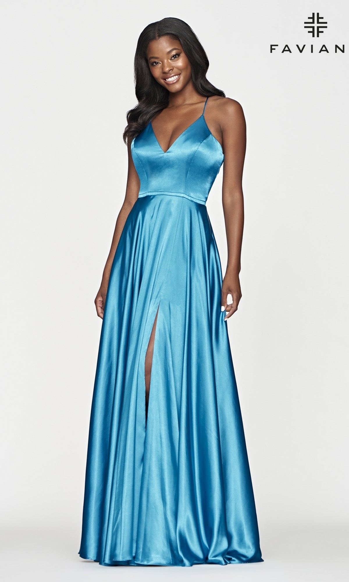 A woman models the Long Faviana Prom Dress—sleeveless, floor-length teal charmeuse with a V-neck, front slit, and back cut-out—standing against a plain backdrop featuring the Faviana logo.